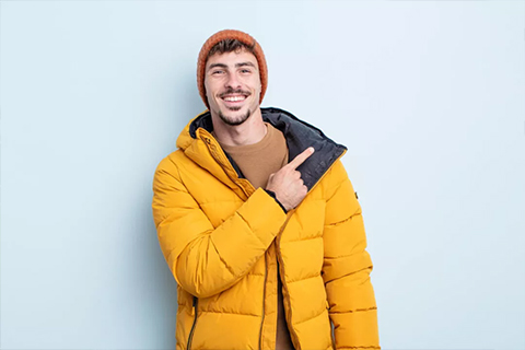 Man lachend met muts wijzend naar rechts. De rest van de tips tegen de winterdip!